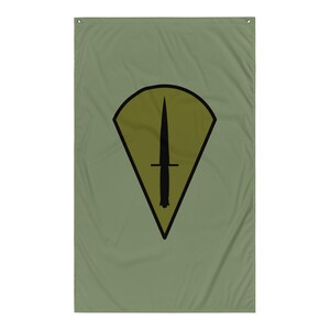 Pode incluir: Bandeira vertical verde-oliva com um emblema de punhal preto dentro de um losango amarelo e preto. O punhal está centrado e tem uma pega detalhada. A bandeira é retangular.