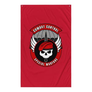 以下が含まれることがあります： 赤色の旗。Combat Control Special Warfareのエンブレムが特徴です。エンブレムには、赤いベレー帽をかぶった骸骨、パラシュート、翼、そして「Combat Control」と「Special Warfare」の文字が含まれています。