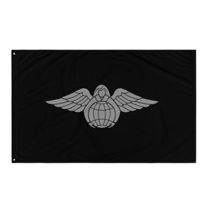 Puede incluir: Bandera negra con un emblema gris que representa una figura alada sosteniendo un globo terráqueo. El emblema está centrado, con las alas extendidas. La bandera tiene ojales para colgar.