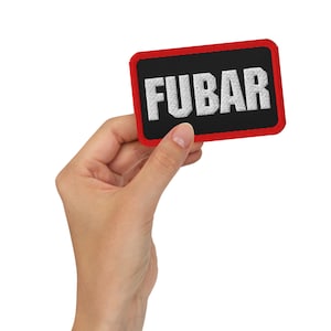 Peut inclure: Un écusson rectangulaire avec un fond noir et une bordure rouge. Le mot "FUBAR" est brodé en lettres blanches et grasses au centre. L'écusson est tenu dans une main sur fond blanc.