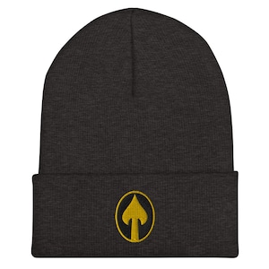 Puede incluir: Un gorro gris oscuro con un círculo bordado amarillo que contiene una flecha amarilla apuntando hacia arriba.