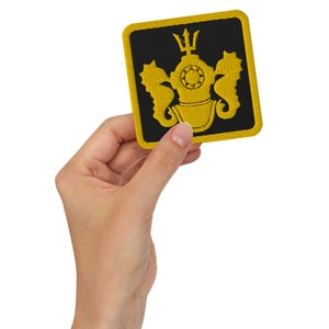 May include: A yellow embroidered patch with a black background. The patch features a diving helmet with a trident on top, flanked by two seahorses.