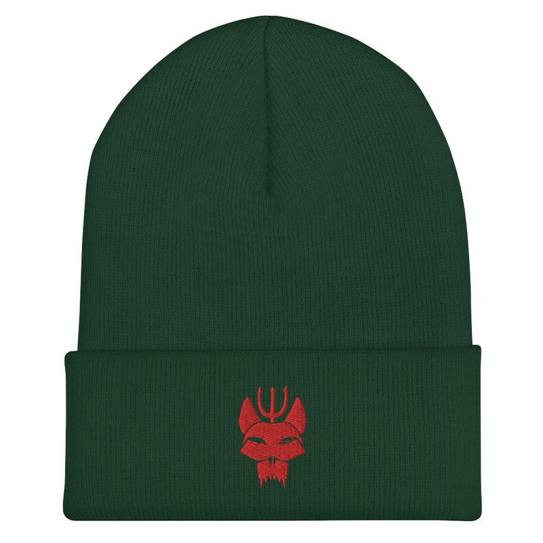 Puede incluir: Un gorro de lana verde oscuro con un logotipo rojo bordado de una calavera con un tridente en la parte superior.
