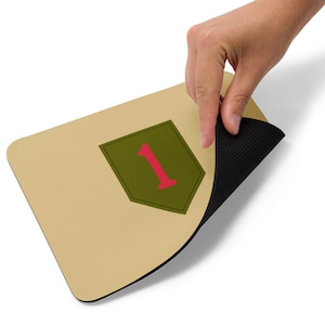 May include: A beige mouse pad with a green and red patch featuring the number "1" in the center. The mouse pad has a black rubber backing.