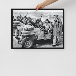 May include: Black and white photograph of a military jeep with soldiers in uniform. The jeep is driving on a dirt road and the soldiers are holding rifles. The soldiers are wearing helmets and have serious expressions on their faces.