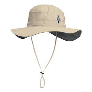May include: A beige sun hat with a wide brim and a dark gray underside. The hat features a mesh panel on the side and a blue and white arrow logo. It has a chin strap with an adjustable toggle.