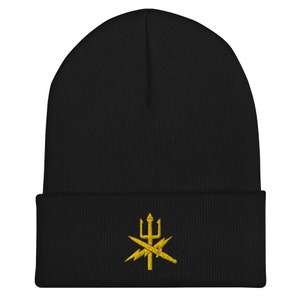 Peut inclure: Bonnet en tricot noir avec un motif brodé en or d'un trident et d'éclairs.