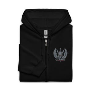 Op de afbeelding: Zwarte hoodie met ritssluiting en een klein geborduurd embleem op de borst. Het embleem toont een gevleugelde schedel en een zwaard, met de tekst "JTAC" eronder. De hoodie heeft een volledige ritssluiting en een capuchon.