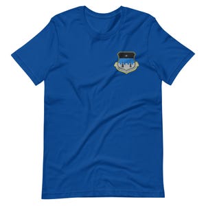 May include: Royal blue t-shirt with a small emblem on the left chest. The emblem is shield-shaped with a black and blue background and a gold border. The emblem has the text "AIR FORCE" and "SPECIAL WARFARE".