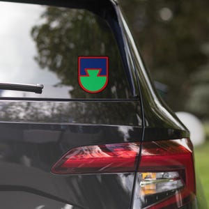 May include: A black car with a red, green, and blue military unit patch sticker on the back window.