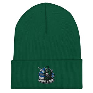 Puede incluir: Un gorro verde con un parche bordado que representa a la muerte en una motocicleta. El parche incluye el texto "GHOST RIDER" en una fuente curva, con un diseño de motocicleta azul y blanco.