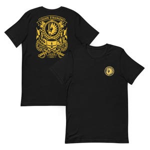 May include: A black short-sleeve t-shirt featuring a gold graphic on the front left chest and a larger gold graphic on the back. The back design displays the text LÉGION ÉTRANGÈRE, HONNEUR, FIDÉLITÉ, VALEUR, 1831, a kepi, a sword, and laurel wreaths.