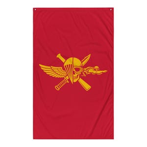 May include: A rectangular red flag featuring a centered yellow graphic. The design displays a split skull wearing goggles, a parachute canopy, a wing, a diving figure, and two crossed knives. The flag has metal grommets in the top corners.