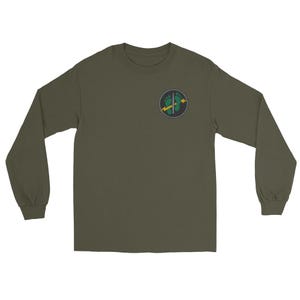 May include: An olive green long-sleeve t-shirt featuring a circular graphic on the left chest. The design displays two green footprints positioned vertically, bisected by a silver sword and a yellow lightning bolt set against a dark background.