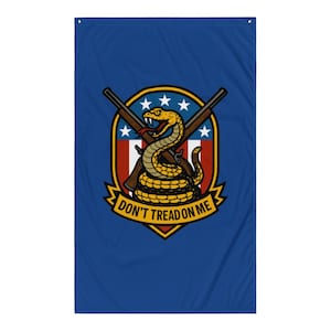 May include: A blue flag featuring a yellow coiled rattlesnake with a red tongue, positioned over crossed rifles and a shield with stars and stripes. The text "DON'T TREAD ON ME" is displayed on a yellow banner.