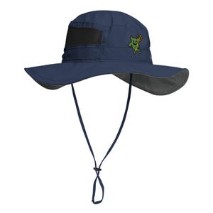 May include: Navy blue sun hat with a wide brim and a black mesh panel. The hat features a green cartoon devil graphic on the front and an adjustable chin strap. The brim is lined with gray fabric.