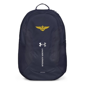 May include: A navy blue Under Armour backpack featuring a silver logo and the text "UNDER ARMOUR" vertically printed on the front. A yellow embroidered emblem depicting an anchor with wings is positioned above the brand logo on the upper section.