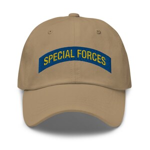 May include: A khaki baseball cap with a blue and gold embroidered patch that says "SPECIAL FORCES".