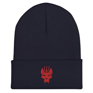 Puede incluir: Un gorro azul marino con un logotipo bordado en rojo de una cabeza de animal estilizada con un tridente encima.