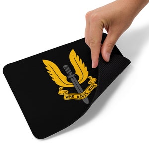 May include: Black mouse pad with a yellow winged dagger and the text "Who Dares Wins".