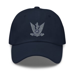 May include: A navy blue baseball cap with an embroidered grey emblem featuring a stylised eagle with a star and the text "צה"ל" in Hebrew.