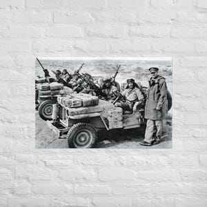 Puede incluir: Una fotografía en blanco y negro de un grupo de soldados con uniforme militar que viajan en un jeep. Los soldados sostienen rifles y miran a la cámara. El jeep conduce por un camino de tierra.