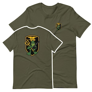 May include: Olive green t-shirts with a cartoon frog graphic. The frog is wearing a helmet and holding a weapon, with a trident and the text "SEAL" above it. The design is on the front and back of the shirt.