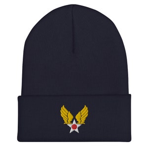 Könnte beinhalten: Marineblaue Strickmütze mit einem gestickten gelben Air Force Flügel- und Stern-Design.