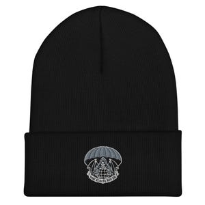 May include: Black beanie with a folded brim. The beanie features an embroidered design of a grim reaper under a parachute, with the text "THAT OTHERS MAY DIE" in a circular pattern below the parachute.