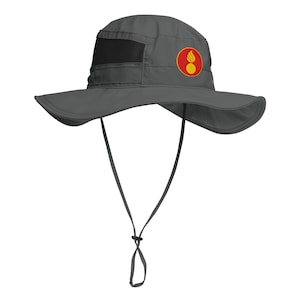 May include: Gray sun hat with a wide brim and a black mesh vent. The hat features a red and yellow circular emblem on the side and a chin strap with an adjustable toggle. This hat is designed for outdoor activities.