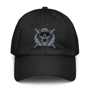 May include: A black baseball cap featuring an embroidered design on the front. The embroidery depicts a skull wearing a diving mask and regulator, positioned in front of two crossed knives, all rendered in shades of grey and black thread.