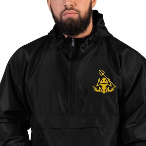 May include: A black quarter-zip windbreaker jacket featuring a hood with adjustable drawstrings. On the left chest, there is a yellow graphic print of a skeletal frog figure holding a trident, positioned against the solid black fabric.