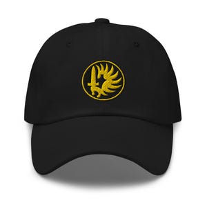 May include: A black baseball cap featuring an embroidered yellow circular emblem on the front. The emblem depicts a vertical sword centered within a stylized wing design, all enclosed by a thin yellow circular border against the black fabric.
