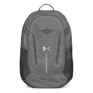 May include: Gray Under Armour backpack with a silver logo and the text "UNDER ARMOUR" printed vertically on the front. The backpack has a black mesh pocket on the side and a silver embroidered patch with the text "160" and a winged sword.