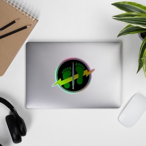 May include: A green and yellow lightning bolt graphic with two green footprints inside a black circle. The circle has a rainbow iridescent border.