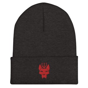 Puede incluir: Un gorro gris oscuro con un logotipo rojo bordado de una cabeza de animal estilizada con un tridente en la parte superior.