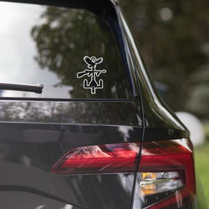 May include: A white vinyl sticker of a bird perched on a rifle with a peace sign at the bottom. The sticker is on the back window of a black car.