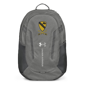 May include: Gray Under Armour backpack with a black mesh side pocket. The backpack features a yellow and black emblem with crossed sabers and a horse head. The Under Armour logo is below the emblem.