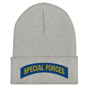 Peut inclure: Un bonnet gris avec un écusson brodé bleu et or qui dit "SPECIAL FORCES".