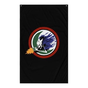 Puede incluir: Bandera negra con un emblema circular que representa una calavera sosteniendo una antorcha. El emblema tiene un borde rojo y verde, con llamas azules que emanan de la cabeza de la calavera. La antorcha emite llamas naranjas y amarillas.