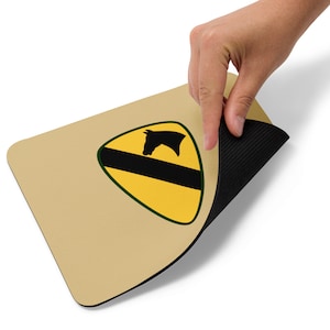 May include: A beige mouse pad with a black and yellow patch featuring a horse head silhouette. The patch is shaped like a triangle with a green border.