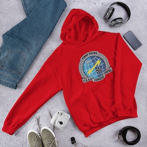 May include: Red hooded sweatshirt with a graphic of a military emblem. The emblem is a circle with a blue and white globe, a lightning bolt, a parachute, and a star. The text around the emblem reads "First There U.S.A.F. Combat Control".