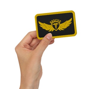 May include: A black and yellow embroidered patch with a medical symbol and wings. The patch says "RESCUE" in yellow lettering.