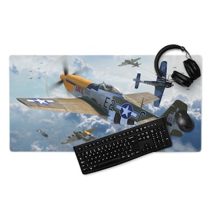 May include: A rectangular mouse mat featuring a vintage airplane design with a black keyboard, mouse, and headphones. The mat showcases a detailed illustration of a World War II fighter plane in flight against a cloudy sky.