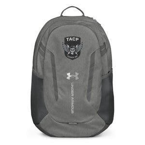Pode incluir: Mochila cinza Under Armour com o texto "TACP" acima de um logotipo de caveira e asas. A mochila tem bolsos laterais de malha e o logotipo Under Armour. O texto "CLEARED HOT" está abaixo do logotipo da caveira.