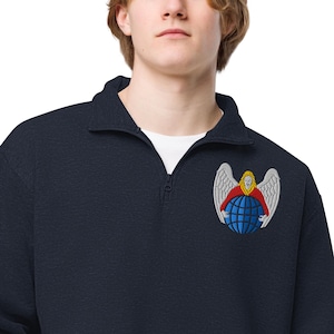 May include: Navy blue quarter-zip sweatshirt with a white collar. The sweatshirt features an embroidered emblem of a woman with wings, a red top, and a blue globe. The emblem is detailed with white, yellow, and blue stitching.