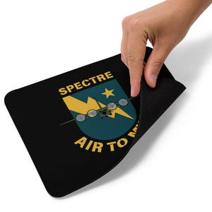 May include: A black mouse mat with a yellow and blue emblem featuring a plane and the text "SPECTRE AIR TO MA".