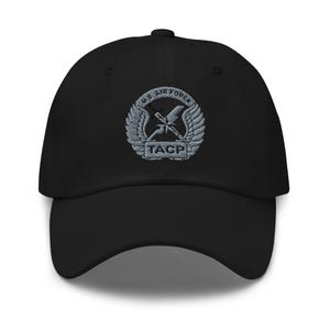 May include: Black baseball cap with a curved brim. The cap features an embroidered emblem with the text "U.S. AIR FORCE" above a design of wings, a lightning bolt, and crossed rifles. The text "TACP" is below the emblem.