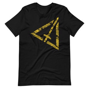 May include: Black t-shirt featuring a gold triangle graphic. The triangle has a distressed, textured appearance.