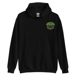 May include: Black hooded sweatshirt with a front pocket and a green emblem on the upper left chest. The emblem features the text "JTAC" and "THEIRS MAY BE". The sweatshirt has a drawstring hood.